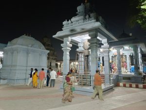 Granite Rajagopuram and stone shrines of Arupadai Veedu Murugan Temple under blue coastal sky in Chennai