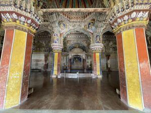 The ornate stucco pillars and painted ceiling arches of the Durbar Hall inside Thanjavur Palace.