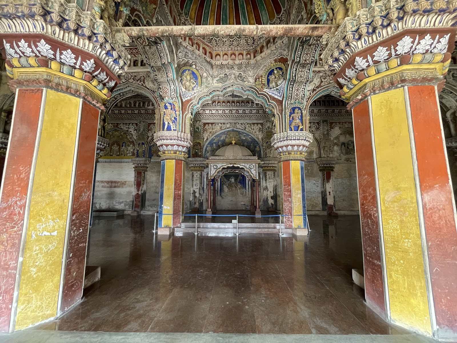 The ornate stucco pillars and painted ceiling arches of the Durbar Hall inside Thanjavur Palace.