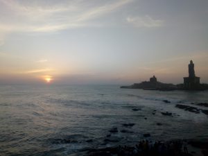 Sunrise emerging over the sea behind Vivekananda Rock Memorial in Kanniyakumari.
