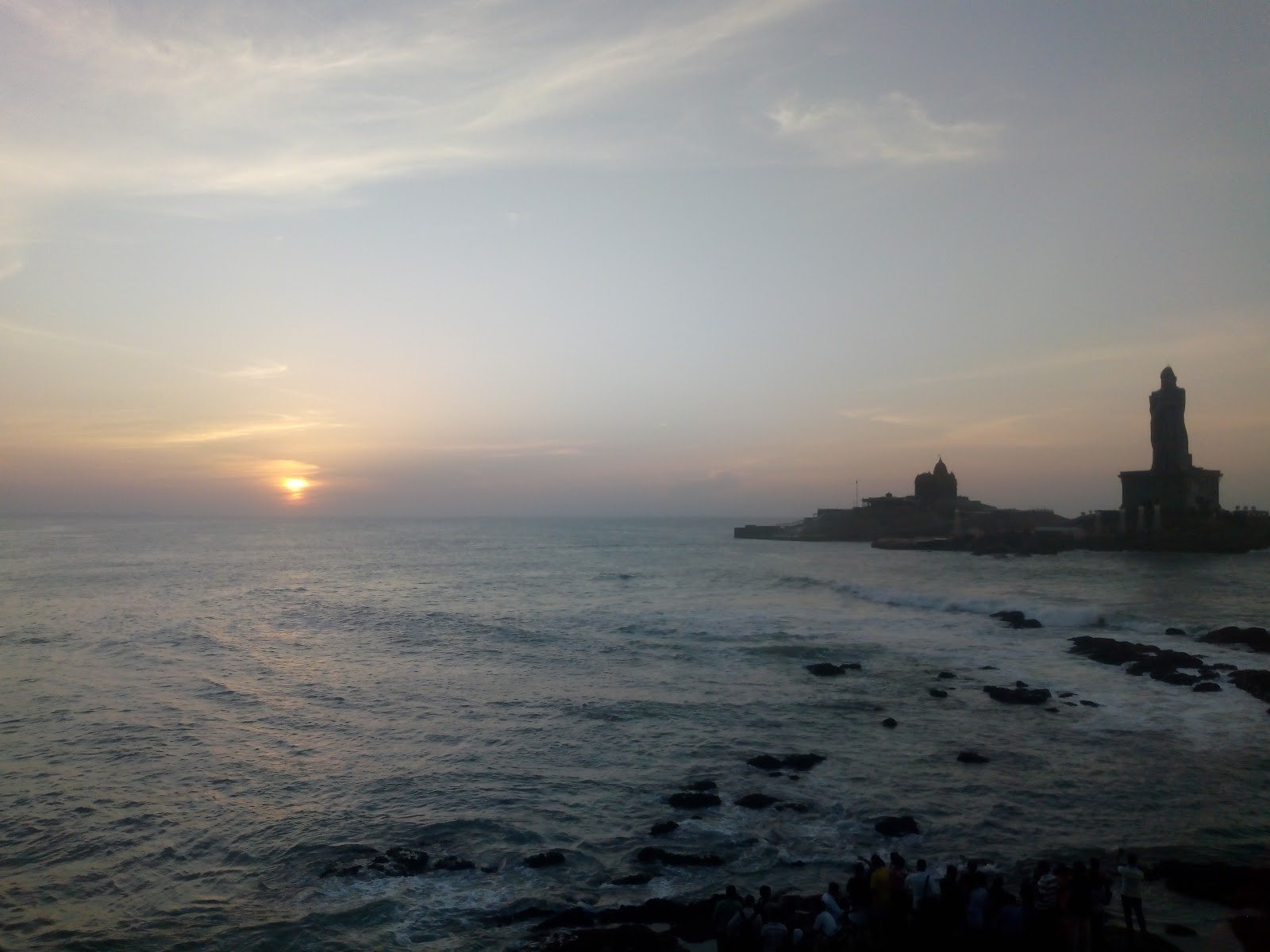 Sunrise emerging over the sea behind Vivekananda Rock Memorial in Kanniyakumari.